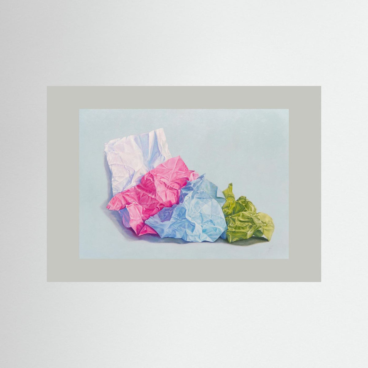 A unframed paper art print depicting crumpled paper in white, pink, blue, and green on a light blue background, presented with a wide gray border/passepartout against a neutral light gray backdrop.