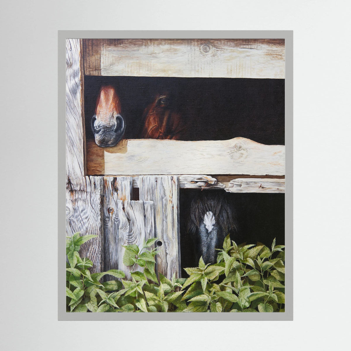 A framed (white frame) paper art print depicting three horses peeking out from rustic wooden stalls, with green foliage in the foreground, shown against a light gray background.