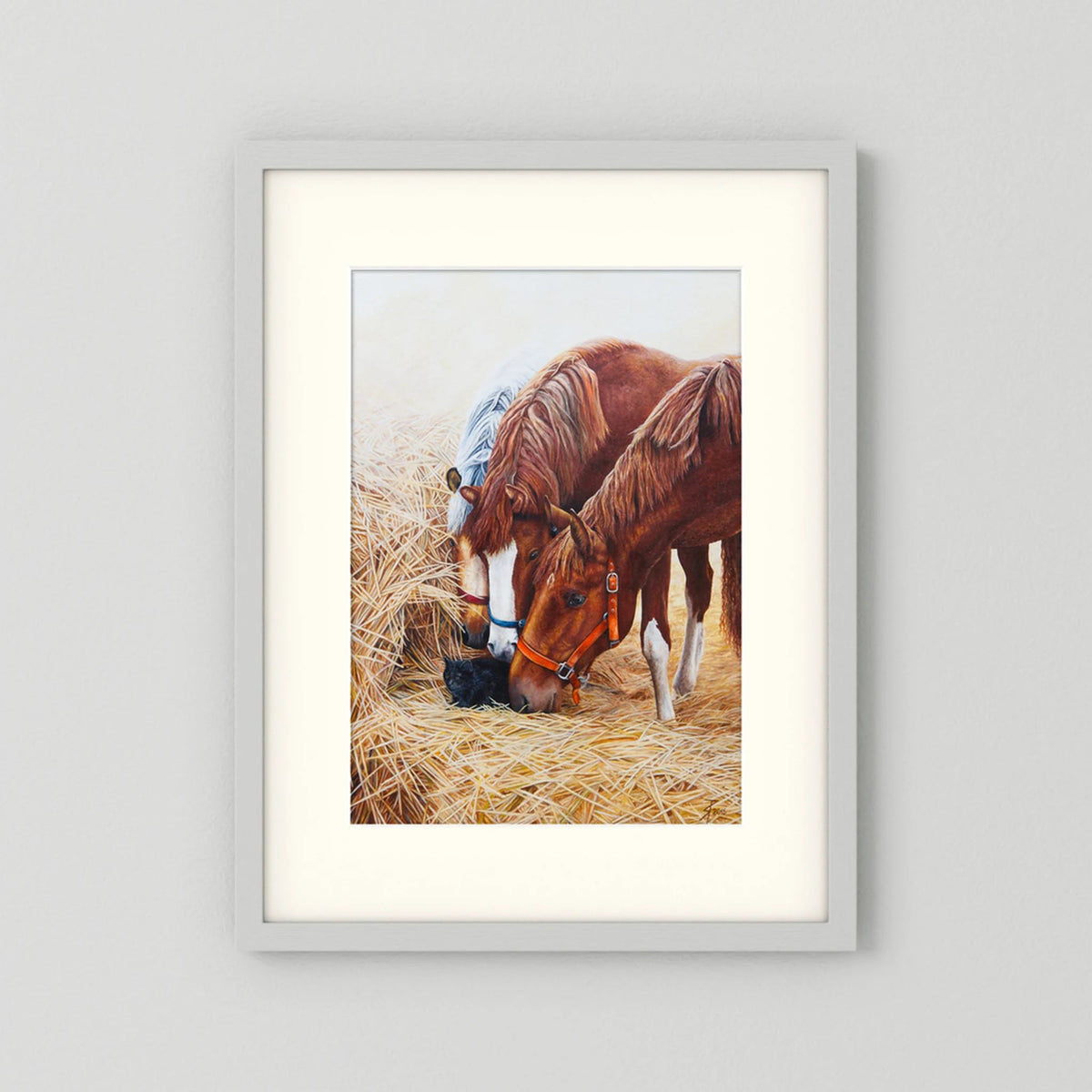 A framed (white frame) paper art print with a freja passepartout featuring a painting of three young horses and a black cat displayed against a neutral light gray background.